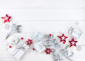 Wall Mural - Christmas composition, border in light colors. Christmas gift, fir branches and cones, stars and snowflakes on wooden white background, top view. Flat lay, copy space.