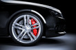 Sports car wheel with red brakes in studio lighting