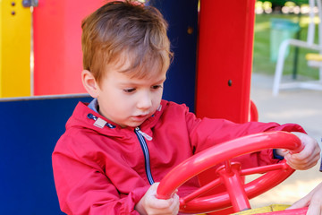 Boy playing on playground car carousel in the amusement park