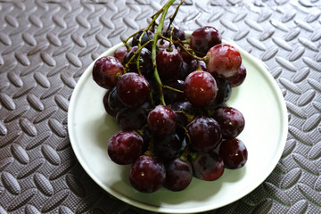 Bunches of fresh ripe red grapes on the dish. Ancient style, a beautiful background with a branch of blue grapes. Red wine grapes. dark grapes, blue grapes, wine grapes