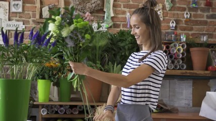 Wall Mural - Florist preparing bouquet for client and checking order off notebook