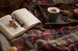 Autumn lifestyle home decor with open book, blanket and hot chocolate or coffee cup