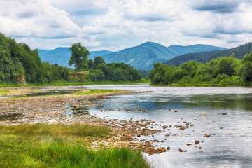 Wall Mural - Mountain river stream of water in the rocks with majestic stormy sky