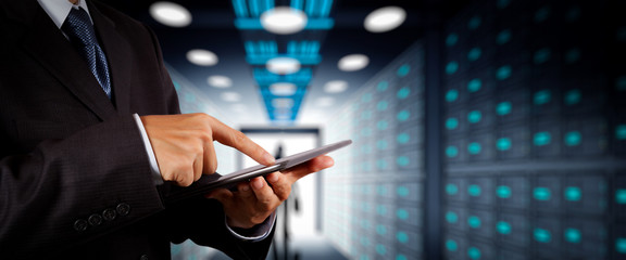 Poster - Businessman working with VR wide blank screen computer on server room in background.