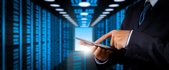 Poster - Businessman working with VR wide blank screen computer on server room in background.