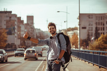 Young Man Traveler Hitchhiking In The City