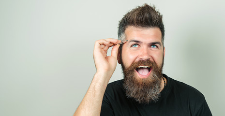 Eyebrow Correction. Closeup Of Beautiful Funny Man Plucking Eyebrows. Portrait Of Sexy Male With Beard Model Face And Tweezers Near Brows. Beauty Concept. High Resolution