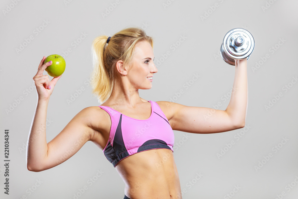 Diet fit body. Girl holds dumbbells and apple fruit - obrazy, fototapety, plakaty 