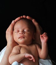 Baby In Mother's Arms Wrapped In White Blanket Stock Photo