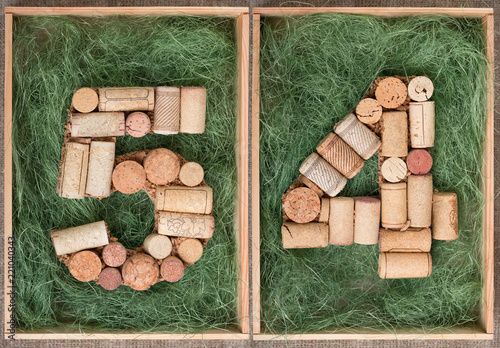 Fotografia Number 54 fifty four made of wine corks on green background in wooden box