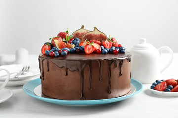 Fresh delicious homemade chocolate cake with berries on table against light background