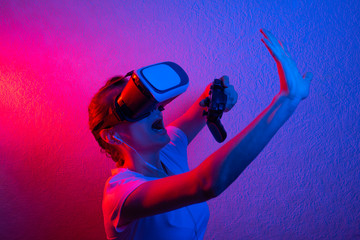 A girl with a gamepad in vr glasses, playing with blue and red light. The concept of innovation and the future