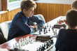 © Natali - cute young boy in blue shirt plays chess in the classroom. Hobby, education, intellectual game.