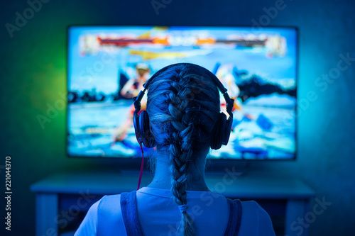 Cuadros en Lienzo A girl is a gamer or a streamer in front of a television playing