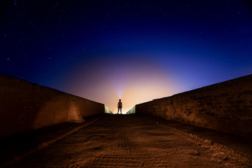 Man crossing bridge in the countryside at night