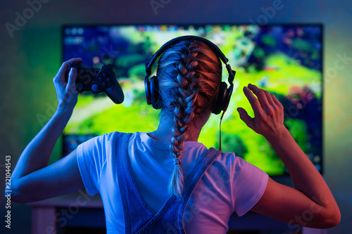 Photo  A gamer or a streamer girl at home in a dark room with a gamepad playing with friends on the networks in video games