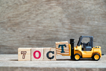 Wall Mural - Toy forklift hold block T to complete word 7 oct on wood background (Concept for calendar date in month October)