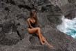 Slender girl sunbathe on the rocks near the ocean
