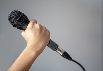 Hand with microphone closeup on gray background