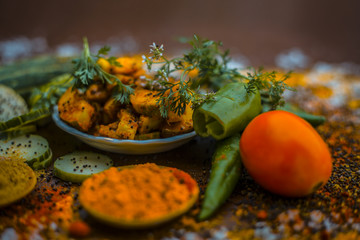 Close up of India's or Asia's popular pickle i.e. Indian pickling cucumber pickle or Indian styled cucumber pickle or salad on wooden surface with all necessary ingredients in dark gothic colors.