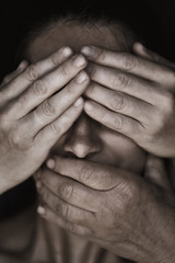 Girl face is closed by people hands, close-up