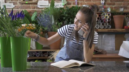 Wall Mural - Young florist taking order over phone and writing it down in notebook