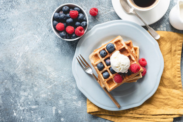 Wall Mural - Belgian waffles with ice cream and berries on concrete background. Top view of sweet tasty breakfast. Copy space for your text