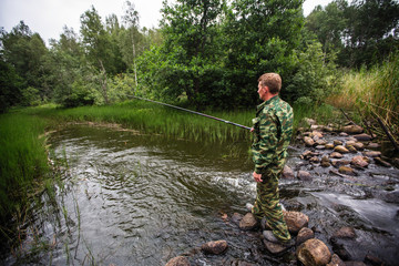 Wall Mural -  Fisherman standing on stones catching fish on the river.