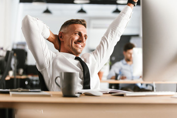 Wall Mural - Smiling middle aged business man relaxing and looking away