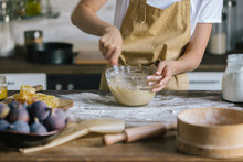 Cropped Shot Of Woman Mixing Dough For Pie On Rustic Wooden Table