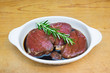 © corners74 - Meat marinating: Beef steak eye fillet in white dish of soy sauce marinade and rosemary herb sprig on wooden background with copy space