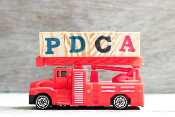 Sticker - Toy fire ladder truck hold letter block in word PDCA (Plan, Do, Check, Act) on wood background