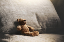 Teddy Bear Sitting Down On Sofa In Retro Filter, Lonely Teddy Bear Sitting Alone On Couch In Living Room At Night,Lonely Concept,Lost Child,International Missing Children's Day.