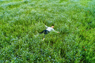 Young beautiful woman relaxing in the field with flowers. Overhead view.