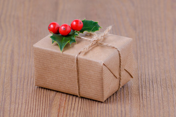 gift box with holly berries on wooden background, selective focus