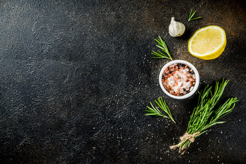 Cooking food ingredients background. Spices, garlic, herbs, olive oil. rusty black stone table. Copy space above