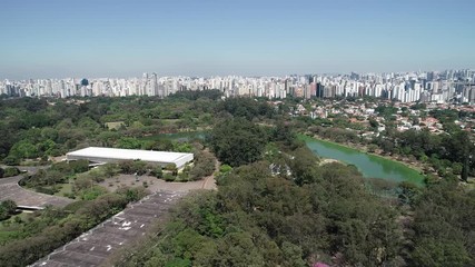 Wall Mural - Aerial view of Ibirapuera park in Sao Paulo city, Brazil. Prevervetion area with trees and green area of Ibirapuera park. Office buildings and apartments in the background on a sunny day.
