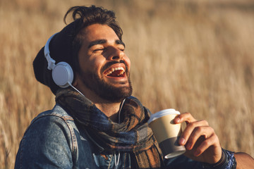 Closeup of young man listens to music  in the meadow