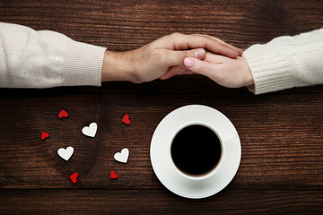 Wall Mural - Female and male hand holding each other with cup of coffee