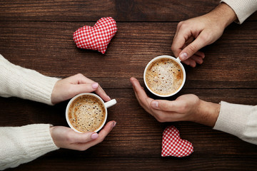 Wall Mural - Female and male hand holding cups of coffee with red fabric hearts
