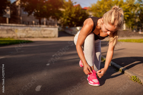 Fotografía Young woman athlete tying sneakers on running track on sportsground in summer