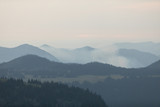 Fototapeta Krajobraz - Mountains with trees, clouds and haze