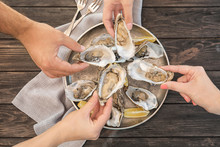 Top View Of People With Fresh Oysters At Table, Focus On Hands
