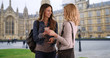 © rocketclips - Two white girls browsing social media together on phone near Westminster Palace