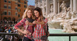 © Mark Adams - Smiling young Caucasian women taking selfie photo together by Trevi Fountain