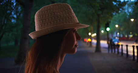 Wall Mural - Silhouette of young woman in fedora hat outdoors in evening