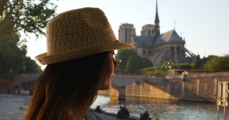 Wall Mural - Side view of tourist woman near Notre Dame Cathedral looking out at the Seine