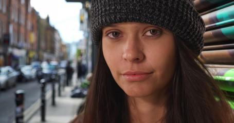 Wall Mural - Close up portrait of girl wearing beanie looking at camera on urban city street