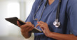 © Mark Adams - Close up of woman nurse or doctor working on tablet computer inside hospital