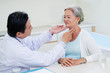 © DragonImages - Doctor examining throat of senior woman during regual check-up